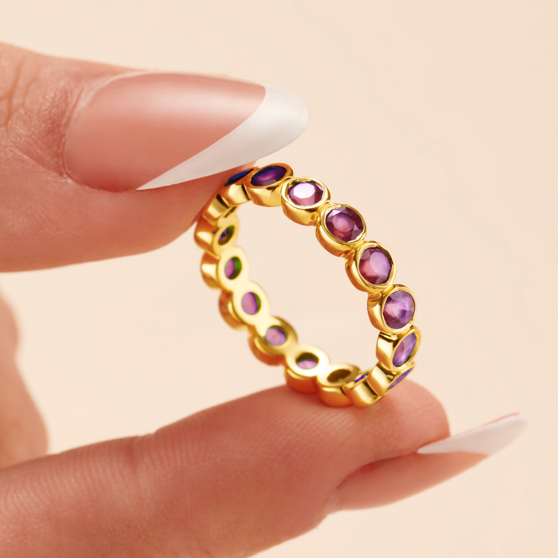 Amethyst gemstone full eternity ring held by model